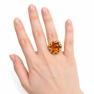 Anello da donna in oro giallo con grande pietra arancio indossato alla mano
